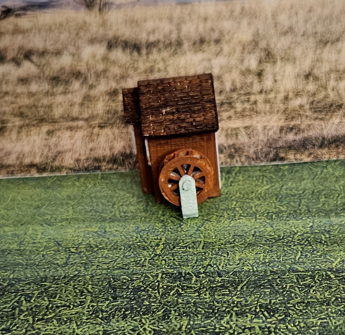 Side view of N scale waterwheel with medium building